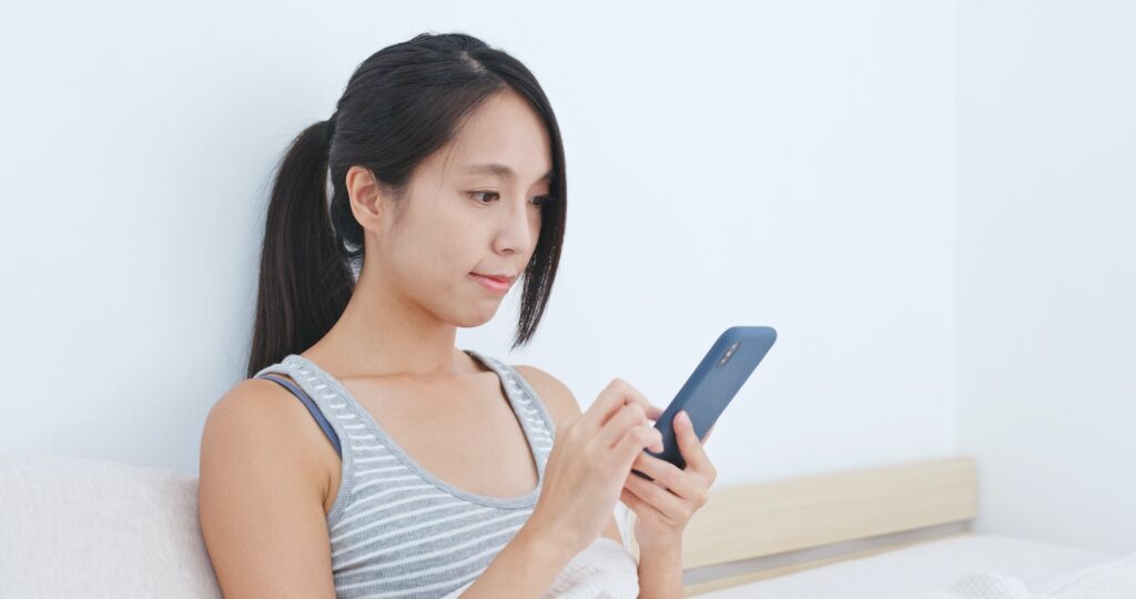 Woman using mobile phone app to control the lighting at home, smart home concept